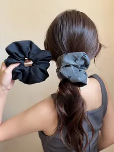 Vista dettagliata di scrunchie in tessuto nero e grigio con fiocchi portati a coda di cavallo