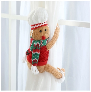Macro detail of gingerbread man curtain tieback with red and green knitted scarf decor