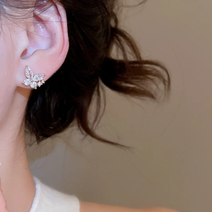 Close-up of gold-plated butterfly stud earrings with sparkling cubic zirconia on model