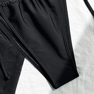 Macro detail showing fine stitching and pleated texture of high-elastic black bikini fabric