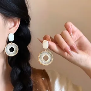 Vue détaillée de boucles d'oreilles bohèmes avec fil de soie jaune et bordure perlée