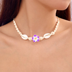 Detail of bohemian woven necklace with purple frangipani flower, shells and wooden beads