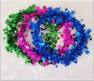 Macro detail of star-shaped Christmas tinsel garlands in green, rose, and blue metallic finish