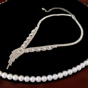 Close-up of silver tassel Y-necklace with rhinestones on a black velvet display