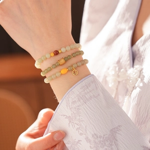 Detailed view of triple-layer Chinese style beaded bracelet with gold Fu pendant and charms