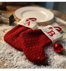 Close-up of red knit Christmas stockings with white cuffs and letters A and B in snow