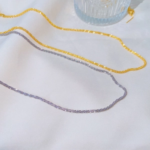 Macro shot of fine sparkling gold and silver twisted star chains on white fabric