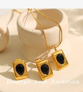 Detail of 18K gold-plated necklace and earrings set with black teardrop pendants