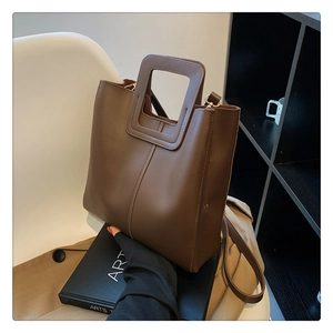 Brown leather bucket bag detail with unique square cutout handle and crossbody strap