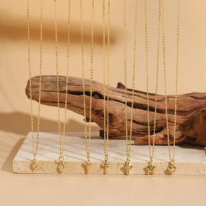 Elegant gold necklaces with star and heart pendants displayed on a beige stone slab