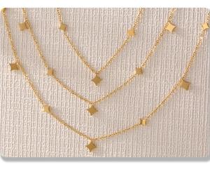 Detailed close-up of golden multi-layered star necklace with rhombic star pendants