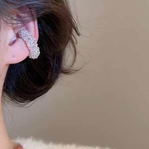 Detailed close-up of a clear faceted beaded C-shape ear cuff worn on the earlobe