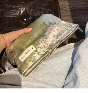 Macro shot of satin cosmetic bag with floral embroidery and gold zipper detail