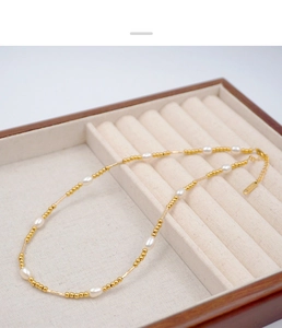Detail of gold pearl necklace with S925 engraved tag in a premium wooden jewelry box