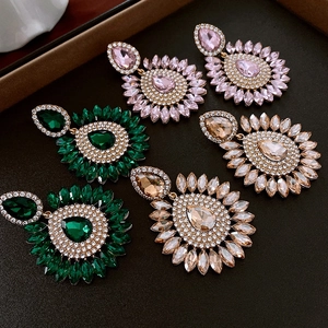 Gros plan détaillé de boucles d'oreilles gouttes avec cristaux rose, émeraude et champagne