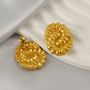 Detailed view of gold oval stud earrings with unique wave texture on a silk display
