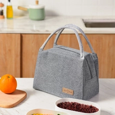Close-up of gray insulated lunch bag on a marble countertop with fresh fruit accessories