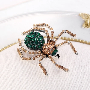 Vintage spider brooch with green crystal belly and champagne rhinestones on silver base