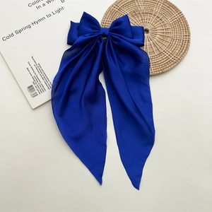 Detail of royal blue satin bow hair clip with long ribbons on a white background