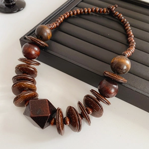 Detail shot of vintage dark brown wood beads and geometric faceted pendant on black tray