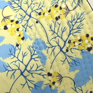 Gros plan du tissu de chapeau bob à fleurs avec base jaune et surpiqûres précises