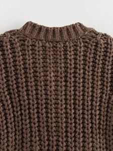 Detailed close-up of brown chunky knit sweater vest showing crew neck and cable textures