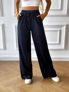 Detail view of navy blue wide-leg trousers with elastic waistband and drawstring cords