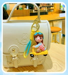 Cartoon girl on yellow scooter silicone keychain with gradient strap on white leather bag