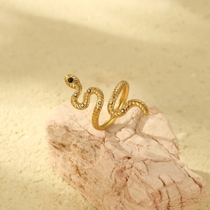 Luxurious 18K gold snake wrap ring with black gems on a natural stone surface