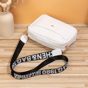 Detailed view of white quilted crossbody bag with stylish patterned wide shoulder strap