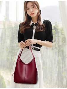 Detail of burgundy leather tote bag showing lychee grain texture and brand patch
