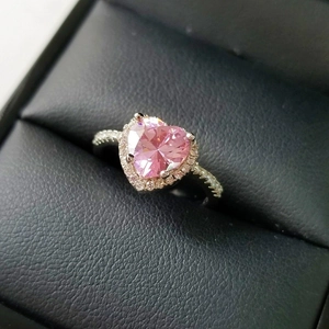 Macro detail of silver ring with large heart-shaped pink stone and diamond halo