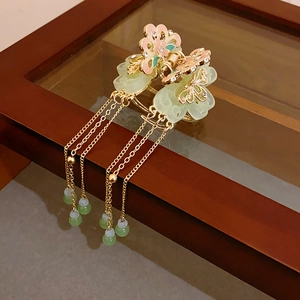 Detailed close-up of golden hair claw clip with floral enamel and pearl tassel fringe