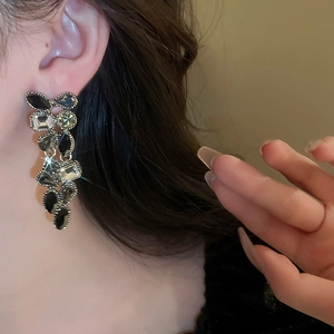Close-up of vintage teardrop drop earrings with dark gemstones worn by a model