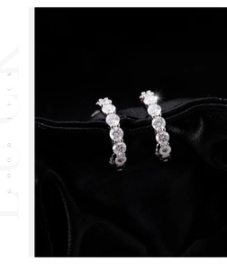 Gros plan de boucles d'oreilles en C en argent avec moissanite sur tissu noir texturé