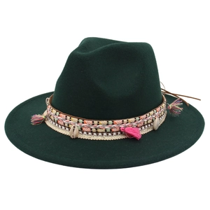 Detail of bohemian woven band with pink tassels and shells on a green wool felt hat