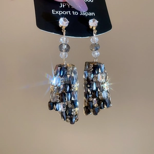 Macro shot of silver drop earrings with geometric pendants and blue zircon pave