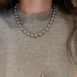 Detail view of a French pearl geometric silver necklace worn over a grey sweater