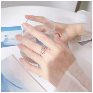 Detail of adjustable silver dolphin open ring worn on finger holding a clear glass