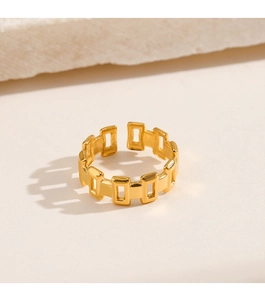 Detail of gold plated hollow rectangular chain link ring on white stone background