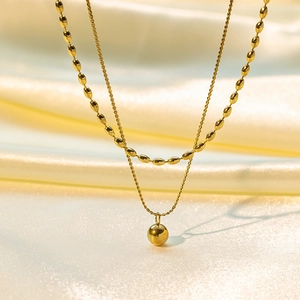 Macro detail of 18K gold double-layer necklace with beads on soft silk background