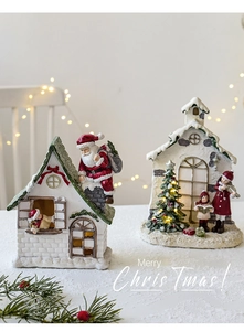 Close-up of resin Christmas house scene with glowing tree and singing figurines