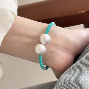 Detailed close-up of retro glass beads and pearls on an adjustable geometric bracelet