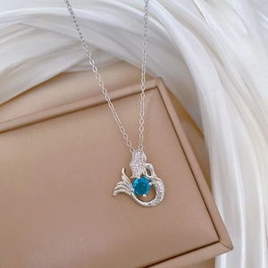 Detailed macro view of mermaid necklace with sapphire blue stone and diamonds
