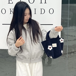 Detail of plush mini handbag with white floral patches and colorful sozakka logo label