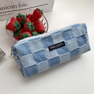 Detail of blue denim checkerboard pencil case with merci paris woven label and white zipper