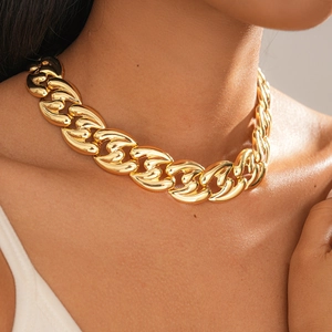 Close-up of a chunky gold metal link necklace styled on a model for a bold fashion look