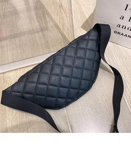 Detail of black quilted leather waist bag with adjustable strap on wooden surface