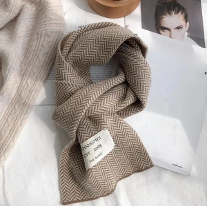 Détail d'une écharpe en tricot marron à chevrons avec étiquette sur fond de magazine stylisé