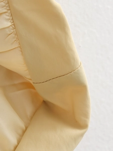 Vue macro d'un tissu jaune clair montrant les coutures détaillées et l'ourlet plissé